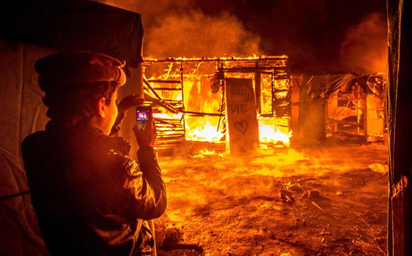 Un niño refugiado de origen sirio, habitante de la "Jungla" de Calais, fotografía una cabaña ardiendo durante los desalojos policiales.